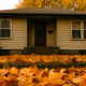 House in the fall with orange leaves on the ground, showing it is fall time.