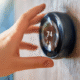 Hand adjusting a smart thermostat set to 74 degrees, illustrating the convenience and energy efficiency of modern home technology for rental properties.