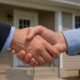 Hands holding a tablet with an upward financial graph in front of a blue and red duplex, symbolizing multi-unit investment growth in Toledo.