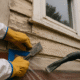 Close-up photo of a worker wearing protective gloves scraping peeling paint from an older Toledo home exterior using lead-safe preparation methods.