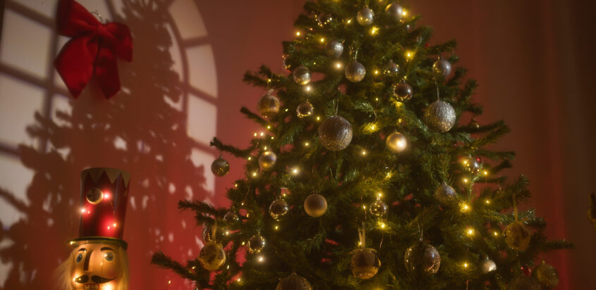 A cozy, safely decorated artificial Christmas tree lit with warm white lights and ornaments, positioned indoors next to a lighted nutcracker figure.