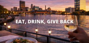Outdoor dining along the Maumee River in downtown Toledo at sunset with food and drinks overlooking the city skyline.