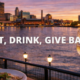 Outdoor dining along the Maumee River in downtown Toledo at sunset with food and drinks overlooking the city skyline.