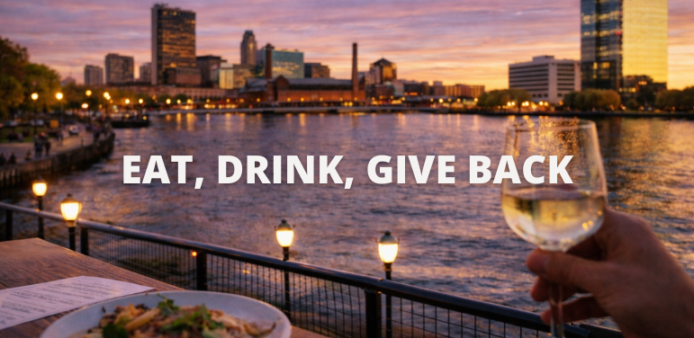 Outdoor dining along the Maumee River in downtown Toledo at sunset with food and drinks overlooking the city skyline.