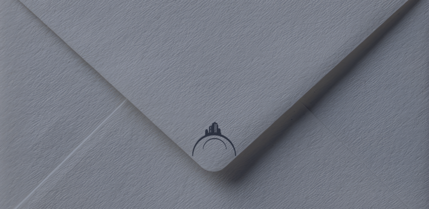 Close-up of a navy envelope with a subtle Buckeye Northwest Realty logo, representing updating your mailing address when moving.
